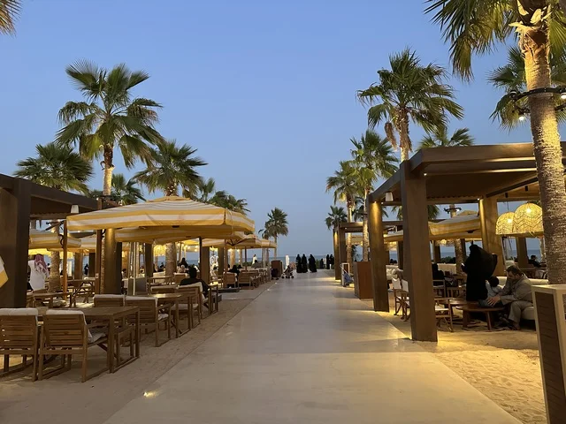 A sandy floor in the seating area, Solt Al-Bahr is a family-friendly recreational and beach destination located on the Corniche Road in Al Khobar, Saudi Arabia. Additional renovations and developments are set for January 3, 2026, featuring a sandy beach with umbrellas and palm trees.