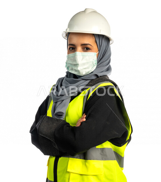 بورتريه مهندسة معمارية عربية سعودية خليجية مكتفة اليدين ، مهندسة انشاءات محجبة ترتدي بدلة السلامة في العمل ، خوذة العمل ، لباس رسمي للعمل ، مشروع بناء ، خلفية بيضاء