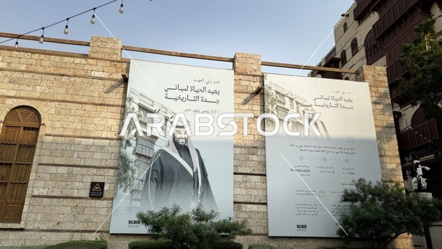 لافتة باللون الأبيض والأسود معلقة على جدار حجري، الفنون المعمارية في المدينة التاريخية في جدة، ت الحارات والتصاميم الشعبية، الأماكن السياحية في المملكة العربية السعودية، المباني الأثرية القديمة، مشاريع إعادة إحياء المنطقة