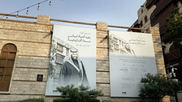 لافتة باللون الأبيض والأسود معلقة على جدار حجري، الفنون المعمارية في المدينة التاريخية في جدة، ت الحارات والتصاميم الشعبية، الأماكن السياحية في المملكة العربية السعودية، المباني الأثرية القديمة، مشاريع إعادة إحياء المنطقة