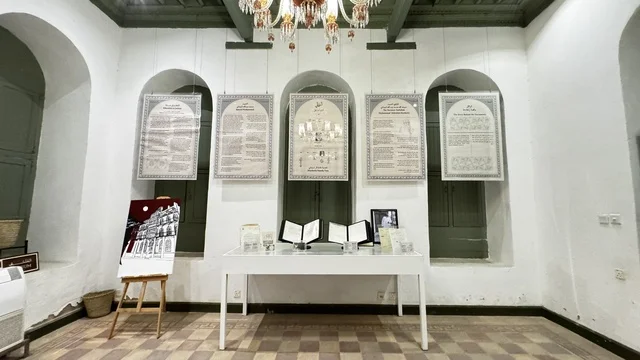 أقواس على الحائط وثريا معلقة في السقف، معلومات في إطار تعليمي أو بحثي، المستندات الشخصية والرسمية، وثائق تاريخية وأرشيفية معروضة في متحف في جدة التاريخية في المملكة العربية السعودية، مقتنيات تذكارية وعناصر ذات قيمة ثقافية.