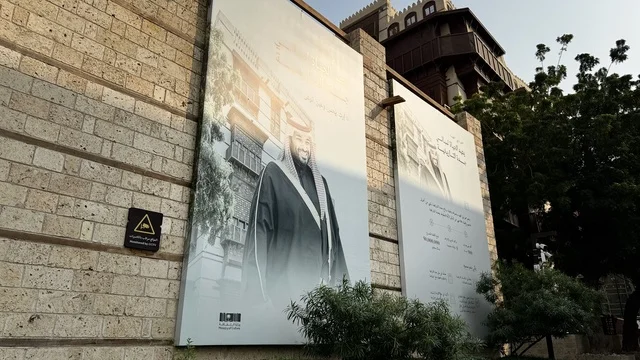 لافتة باللون الأبيض والأسود معلقة على جدار حجري، الفنون المعمارية في المدينة التاريخية في جدة، تصوير درون للحارات والتصاميم الشعبية، الأماكن السياحية في المملكة العربية السعودية، المباني الأثرية القديمة، مشاريع إعادة إحياء المنطقة