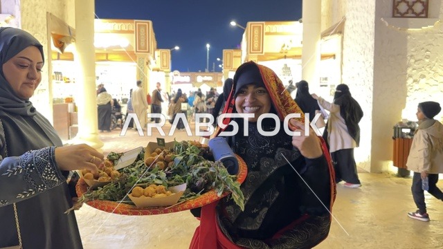 سيدة تقوم بتقديم الطعام في المدينة العالمية يناير 2026 على ضفاف الخليج العربي وبحيرة سيهات في المنطقة الشرقية الدمام، وجهة ترفيهية وثقافية موسمية، مكان لقضاء وقت ممتع مع العائلة
