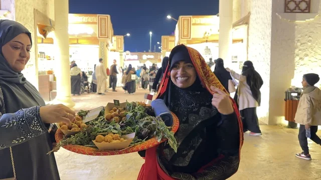 سيدة تقوم بتقديم الطعام في المدينة العالمية يناير 2026 على ضفاف الخليج العربي وبحيرة سيهات في المنطقة الشرقية الدمام، وجهة ترفيهية وثقافية موسمية، مكان لقضاء وقت ممتع مع العائلة