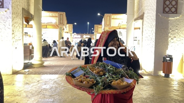 سيدة تقوم بتقديم الطعام في المدينة العالمية يناير 2026 على ضفاف الخليج العربي وبحيرة سيهات في المنطقة الشرقية الدمام، وجهة ترفيهية وثقافية موسمية، مكان لقضاء وقت ممتع مع العائلة
