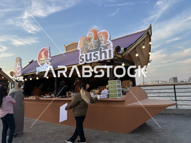 A kiosk selling Chinese food, taste a sushi dish, activate tourism and economic movement, a tourist and entertainment attraction, the global city January 2026 on the shores of the Arabian Gulf and Lake Sehat in the Eastern Province of Dammam, get to know the different cultures of the countries, a place to spend enjoyable time with family.