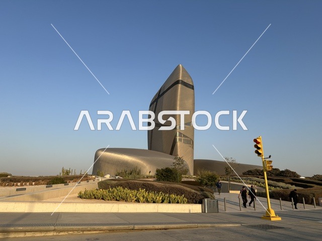 A unique architectural design for a modern cultural landmark, an iconic building with a contemporary metal facade, surrounded by open spaces and pathways, the King Abdulaziz Center for World Culture (Ithra) in the Kingdom of Saudi Arabia.