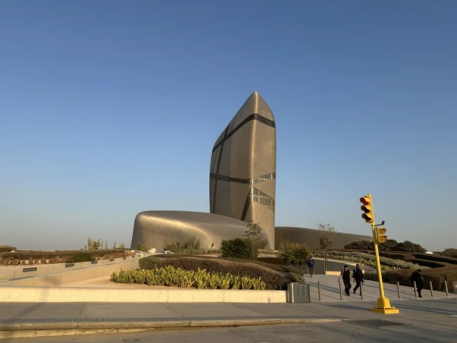 A unique architectural design for a modern cultural landmark, an iconic building with a contemporary metal facade, surrounded by open spaces and pathways, the King Abdulaziz Center for World Culture (Ithra) in the Kingdom of Saudi Arabia.