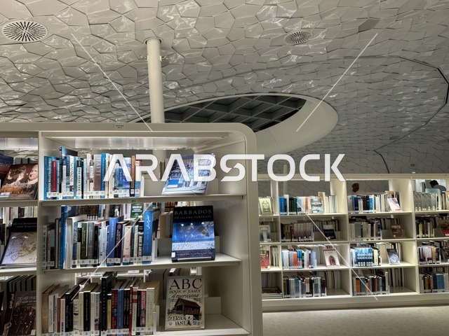 مساحة قراءة ومعرفة بتصميم داخلي عصري، أرفف كتب متنوعة، سقف هندسي مميز يعكس الابتكار المعماري، بيئة تعليمية هادئة، مكتبة مركز الملك عبدالعزيز للثقافة العالمية (إثراء) في الظهران