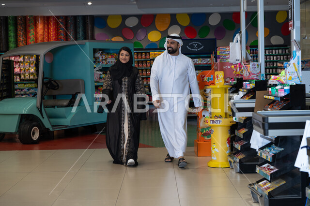 Emirati Couple Walking in a Colorful Supermarket
