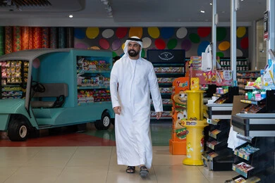 رجل إماراتي يتسوق في متجر حلويات ملون