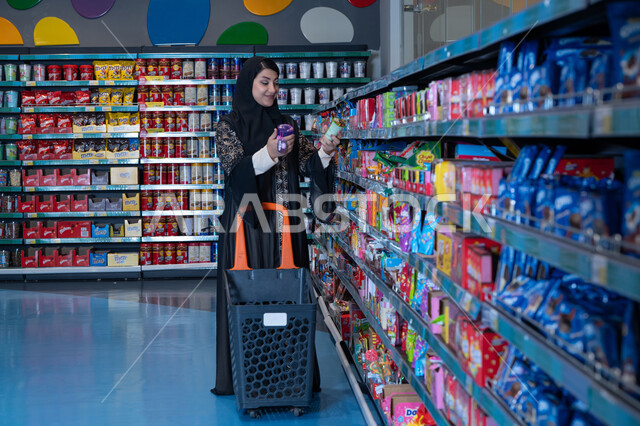 امرأة عربية تتسوق في السوبر ماركت مع عربة تسوق