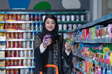 امرأة إماراتية تتسوق في ممر السوبر ماركت