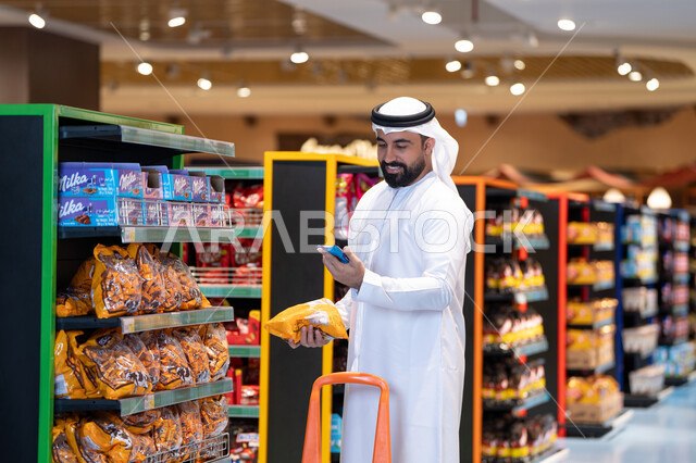 رجل عربي يتسوق في سوبر ماركت باستخدام الهاتف