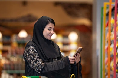 امرأة سعودية تستخدم الهاتف الذكي في السوبر ماركت