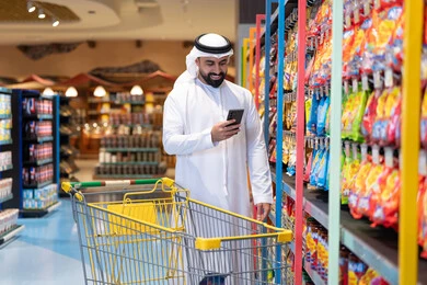 رجل إماراتي يستخدم الهاتف الذكي في السوبر ماركت رجل إماراتي يستخدم الهاتف الذكي في السوبر ماركت