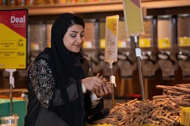 امرأة سعودية تتسوق وتختار القرفة في المتجر