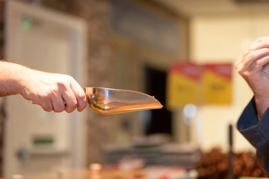 بائع يحمل مغرفة معدنية لخدمة الزبائن في محل تجاري