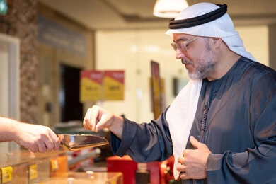 رجل إماراتي يتذوق الطعام في سوق حديث