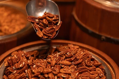 جوز البيكان المقشر في برميل خشبي مع مغرفة معدنية