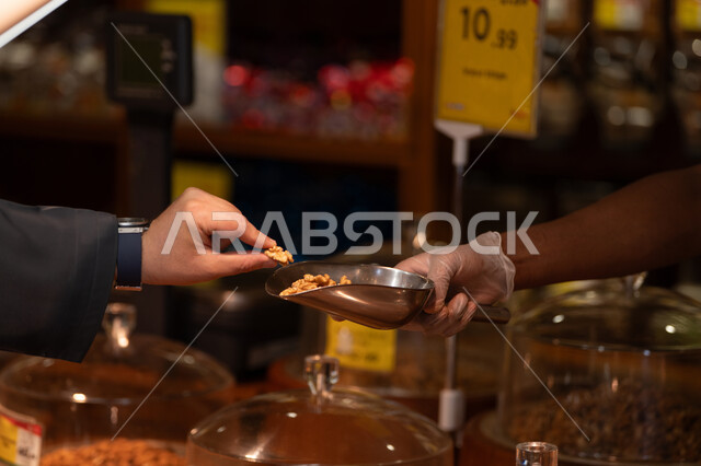 زبون يلتقط حبة جوز من مغرفة في السوق