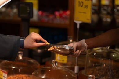 زبون يلتقط حبة جوز من مغرفة في السوق