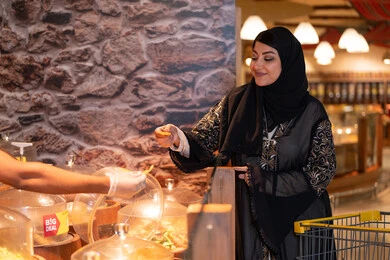 امرأة عربية تتسلم عينة طعام في السوبر ماركت