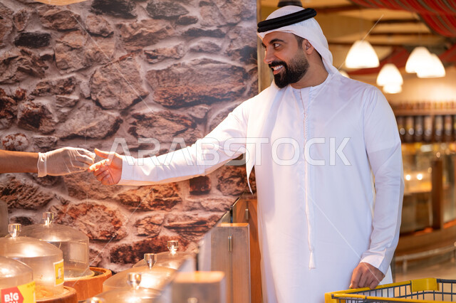 رجل إماراتي يتذوق الطعام في السوبر ماركت