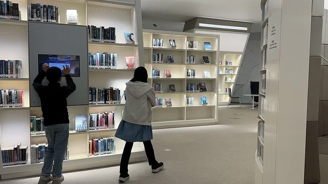 An interactive educational experience for children inside the King Abdulaziz Center for World Culture (Ithra), using digital screens among the bookshelves, a modern knowledge space.