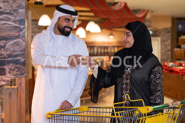 زوج إماراتي بالملابس التقليدية يتسوقان في سوبر ماركت