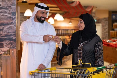 زوج إماراتي بالملابس التقليدية يتسوقان في سوبر ماركت