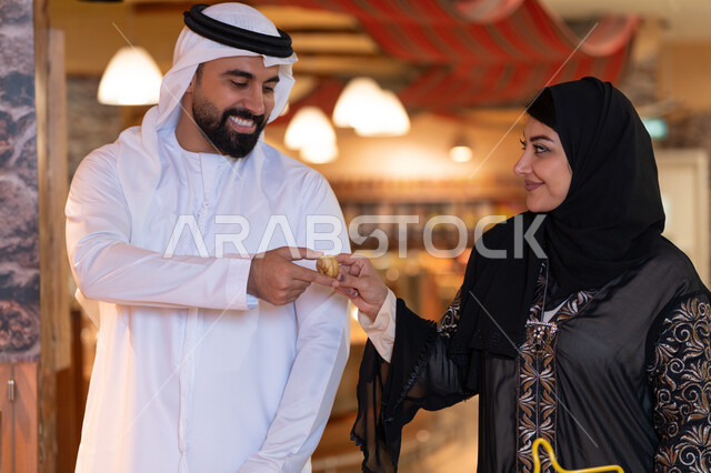 زوج إماراتي يتبادلان التمر بالملابس التقليدية