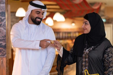 زوج إماراتي يتبادلان التمر بالملابس التقليدية