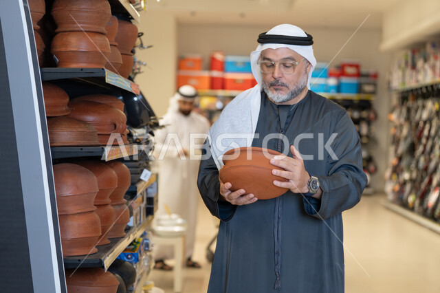 رجل إماراتي يتسوق الأواني الفخارية في المتجر