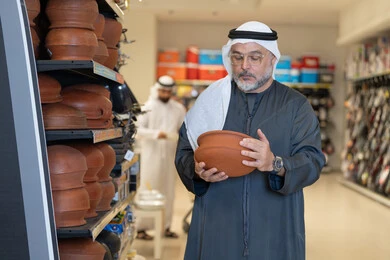 Emirati Man Inspecting Clay Pottery in Store