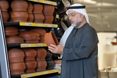 Emirati Man Examining Clay Pottery in Retail Store