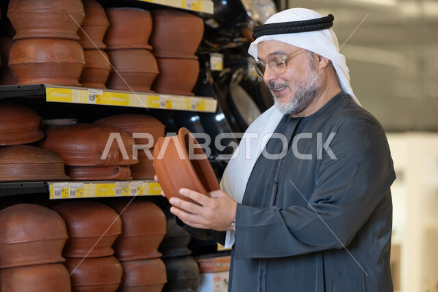 رجل إماراتي يتفحص الأواني الفخارية التقليدية