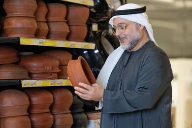 Emirati Man Inspecting Traditional Clay Pottery