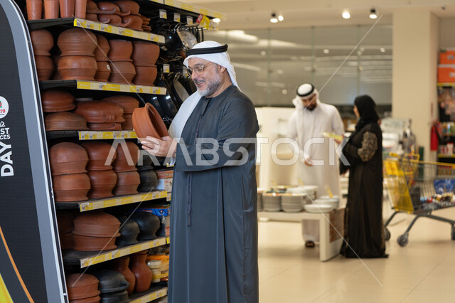رجل إماراتي يتسوق أواني فخارية في متجر حديث