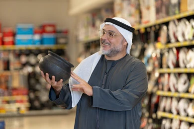 رجل عربي مسن يتسوق أواني منزلية في السوبر ماركت