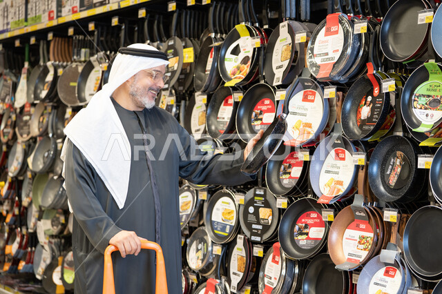 رجل إماراتي يتسوق أواني الطبخ في السوبر ماركت