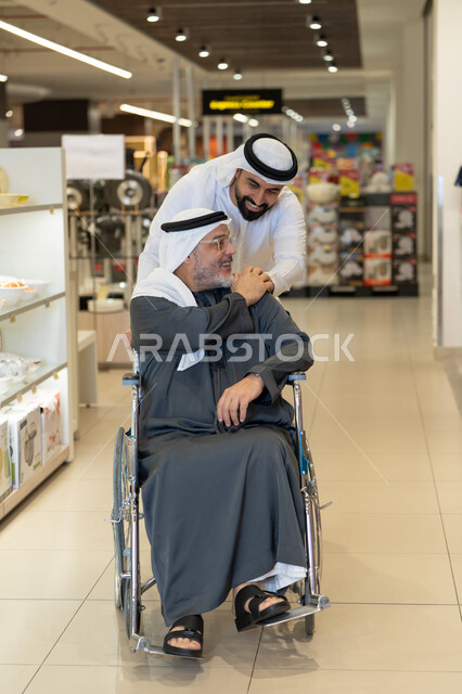 رجال إماراتيون يتسوقون مع كرسي متحرك في متجر