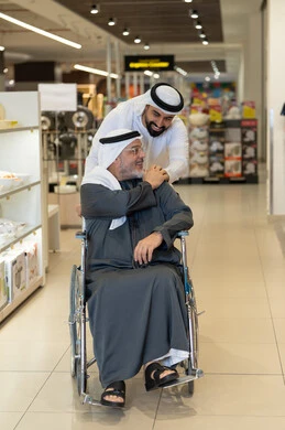 رجال إماراتيون يتسوقون مع كرسي متحرك في متجر