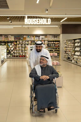 رجل إماراتي يساعد مسناً على كرسي متحرك في السوبر ماركت