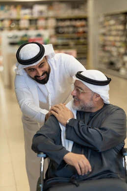شاب إماراتي يساعد والده المسن على كرسي متحرك