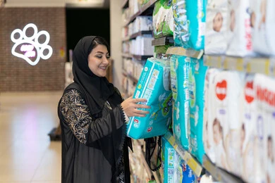 امرأة عربية تتسوق حفاضات أطفال في السوبر ماركت