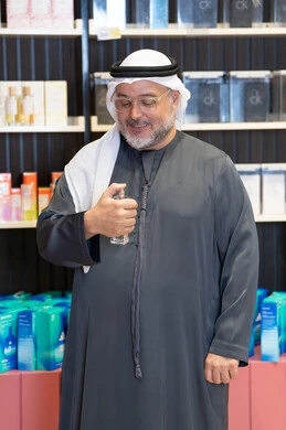 رجل إماراتي يختبر العطور في متجر بيع بالتجزئة