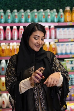 Arab Woman in Abaya Testing Perfume in Beauty Store Aisle