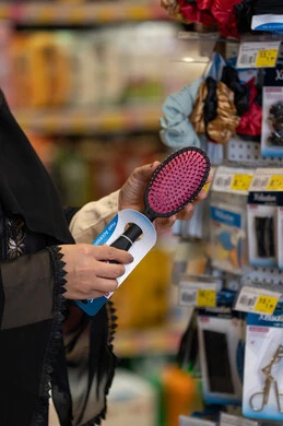 امرأة سعودية تتسوق فرشاة شعر في متجر