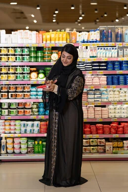 امرأة سعودية تتسوق منتجات العناية بالبشرة في السوبر ماركت